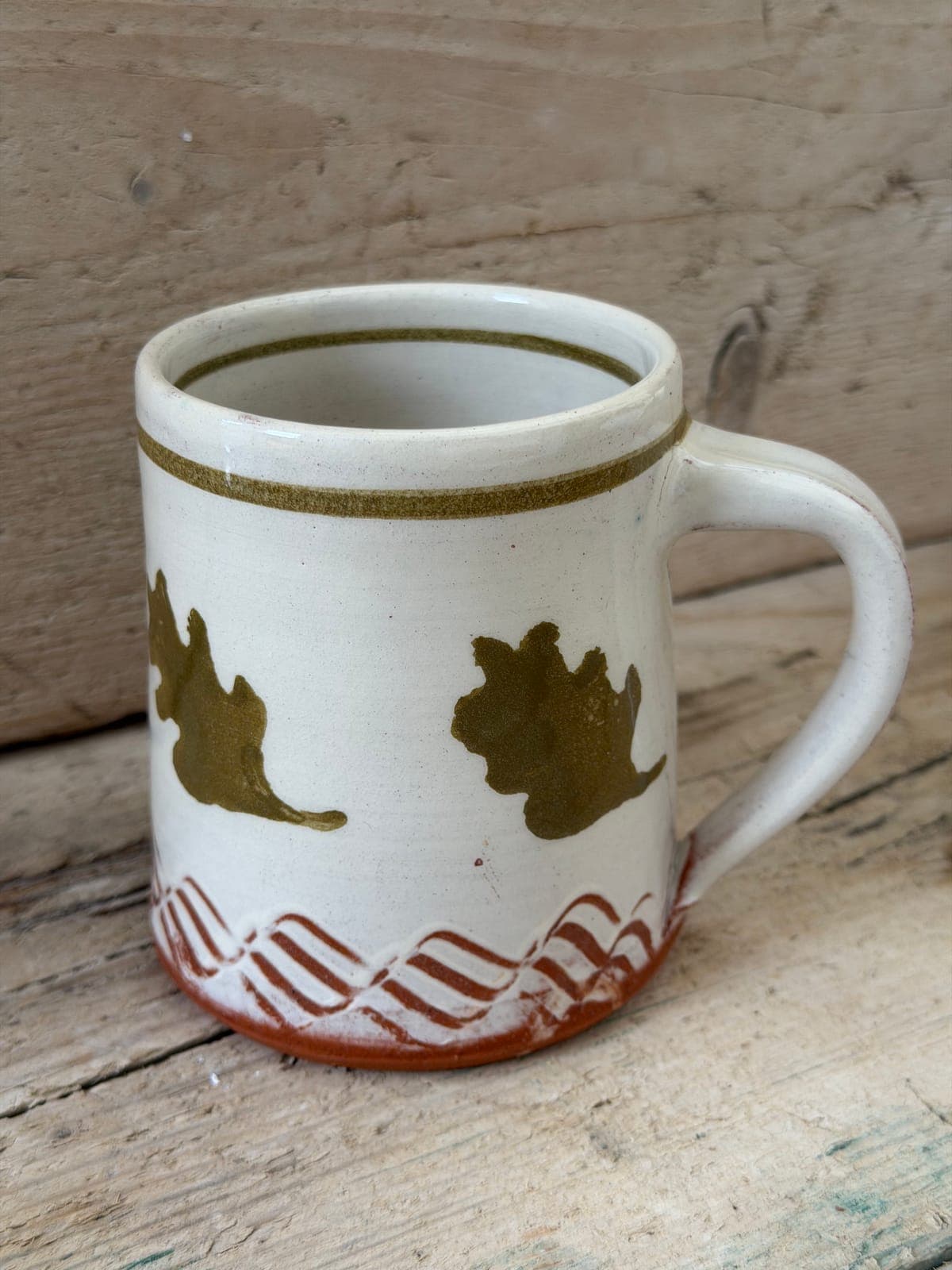 Oak Leaf slipware mug upright with the handle to the right, cream slip decorated with olive oak leaves over a combed terracotta band